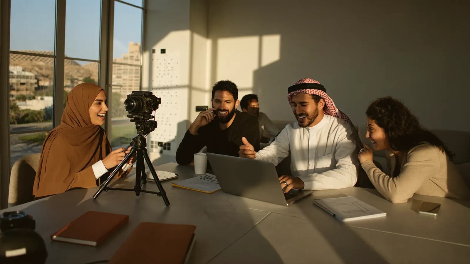 أربعة صنّاع محتوى عرب يعملون معًا حول طاولة عليها كاميرا وحاسوب